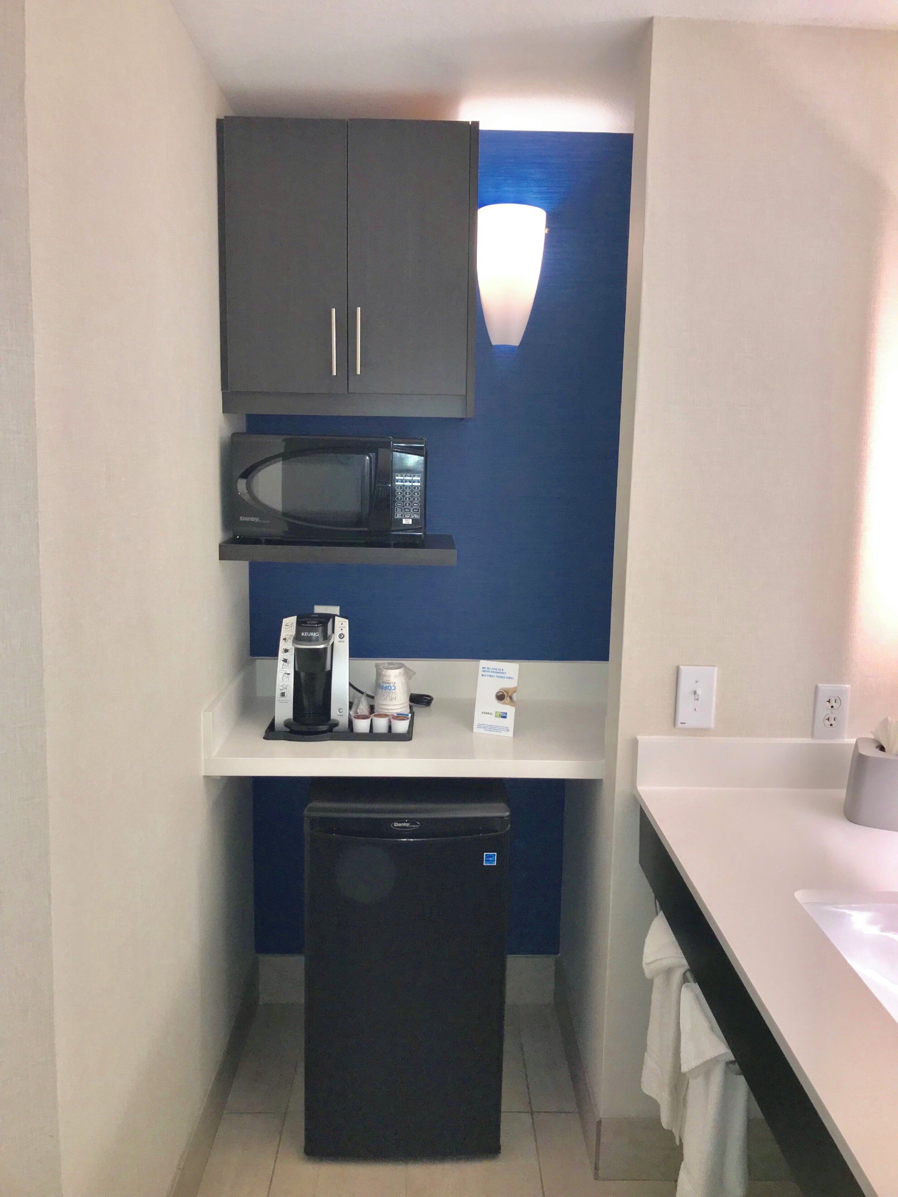 A compact kitchenette with a microwave, coffee maker, and a small refrigerator.