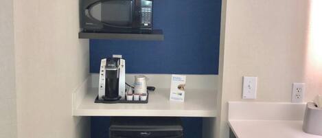 A compact kitchenette with a microwave, coffee maker, and a small refrigerator.