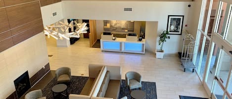 A hotel lobby with seating, a reception desk, and a kitchen area.