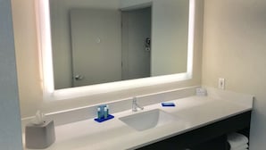 A modern bathroom with a large mirror, white sink, and a towel rack.
