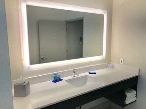 A modern bathroom with a large mirror, white sink, and a towel rack. - Holiday Inn Express Hotel & Suites Tracy by IHG (Tracy)