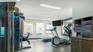 A gym with exercise equipment, a treadmill, and a mirrored wall. - La Quinta Inn & Suites by Wyndham Dallas - Las Colinas (Irving)