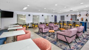 A modern lounge area with seating arrangements, tables, and a bar counter. - La Quinta Inn & Suites by Wyndham Dallas - Las Colinas (Irving)