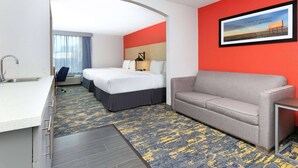 A hotel room with a bed, a sofa, a desk with a sink, and a framed picture on the wall. - La Quinta Inn & Suites by Wyndham Dallas - Las Colinas (Irving)