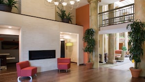 A spacious lobby with a modern chandelier, seating area, and potted plants.