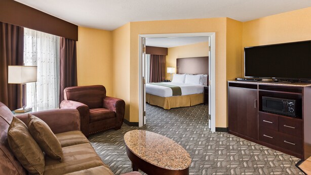 A hotel room with a bed, a TV, a desk, and a sofa.