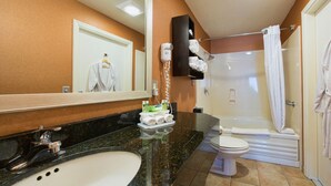 A bathroom with a sink, mirror, toiletries, a shower, and a toilet.