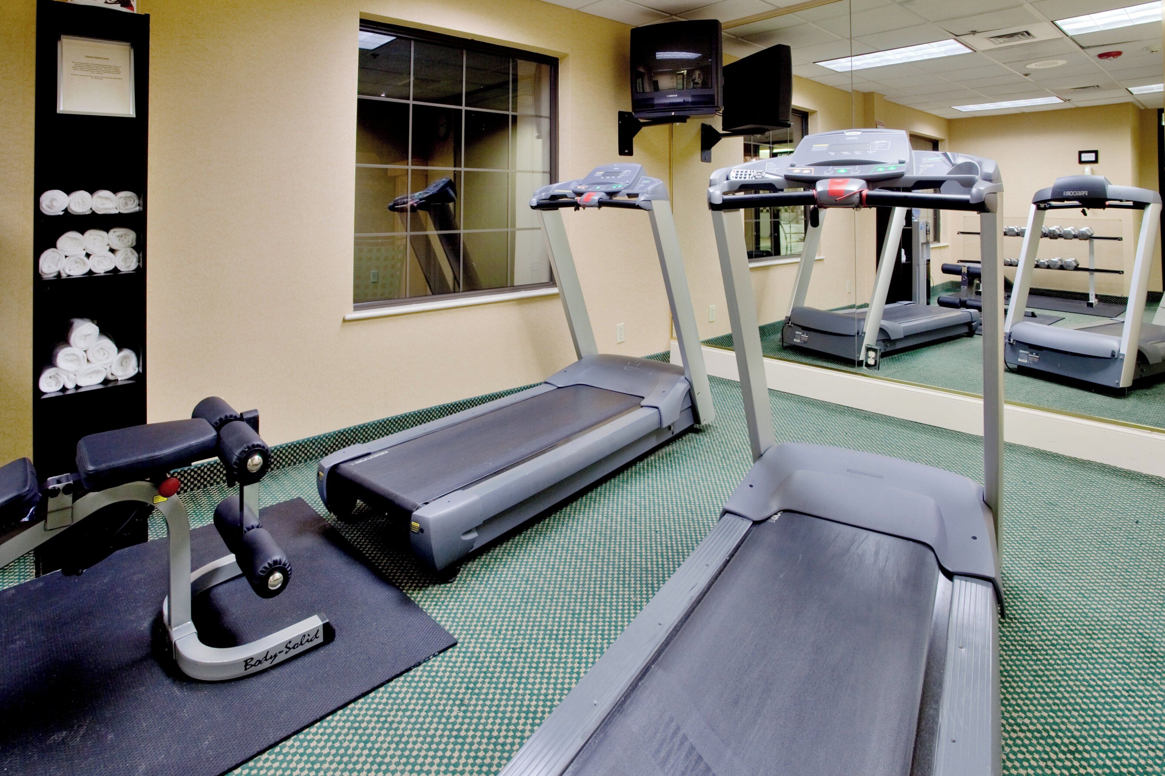 Un gimnasio con cintas de correr, una bicicleta estática y una máquina de remo.