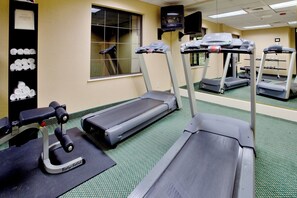 A gym with treadmills, a stationary bike, and a rowing machine.