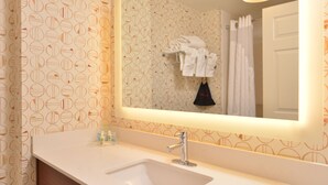 A bathroom with a white sink, a mirror, and a towel rack with white towels. - Holiday Inn Hotel & Suites Raleigh / Cary by IHG (Cary)