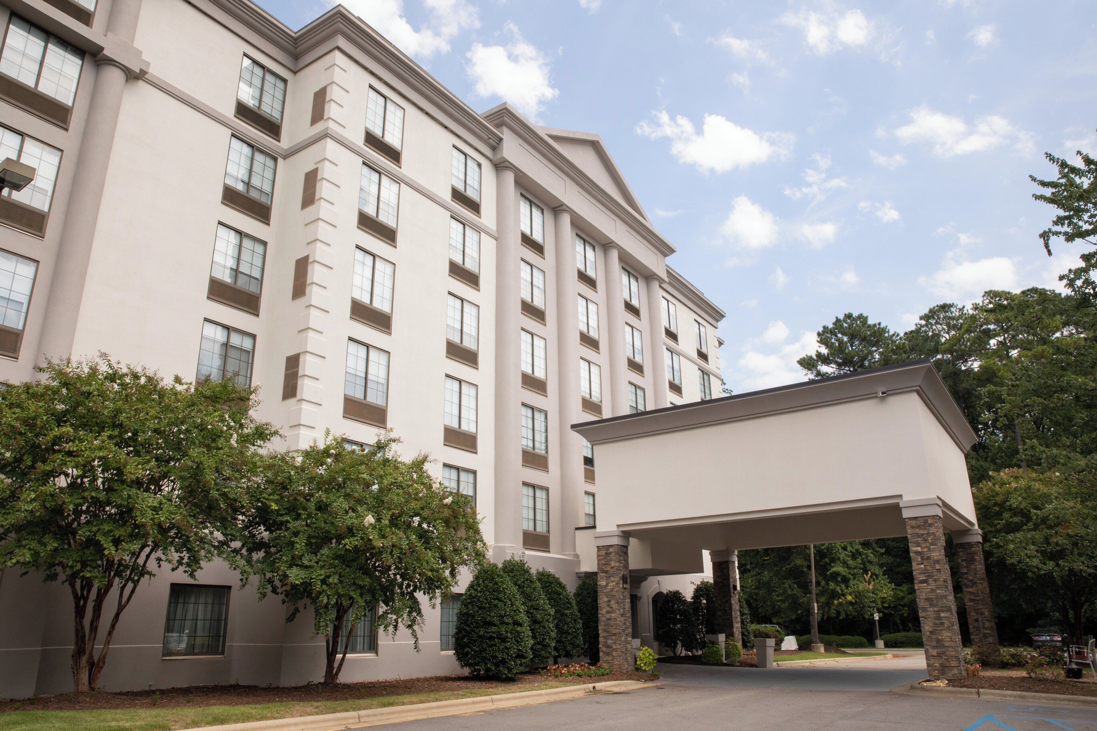 A multi-story hotel with a covered entrance and a parking area.