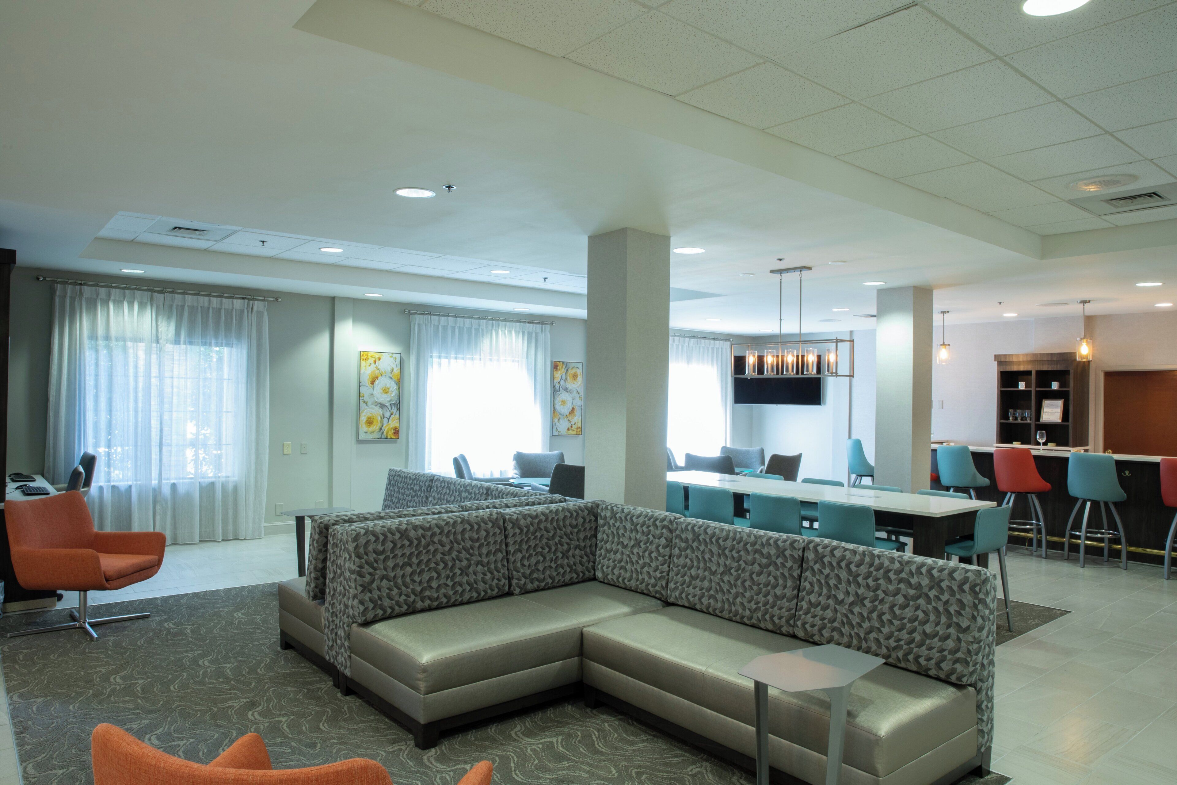En moderne hotellobby med en modulsofa, barområde og spiseplads.