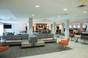 Un moderno vestíbulo de hotel con zona de estar, bar y comedor.