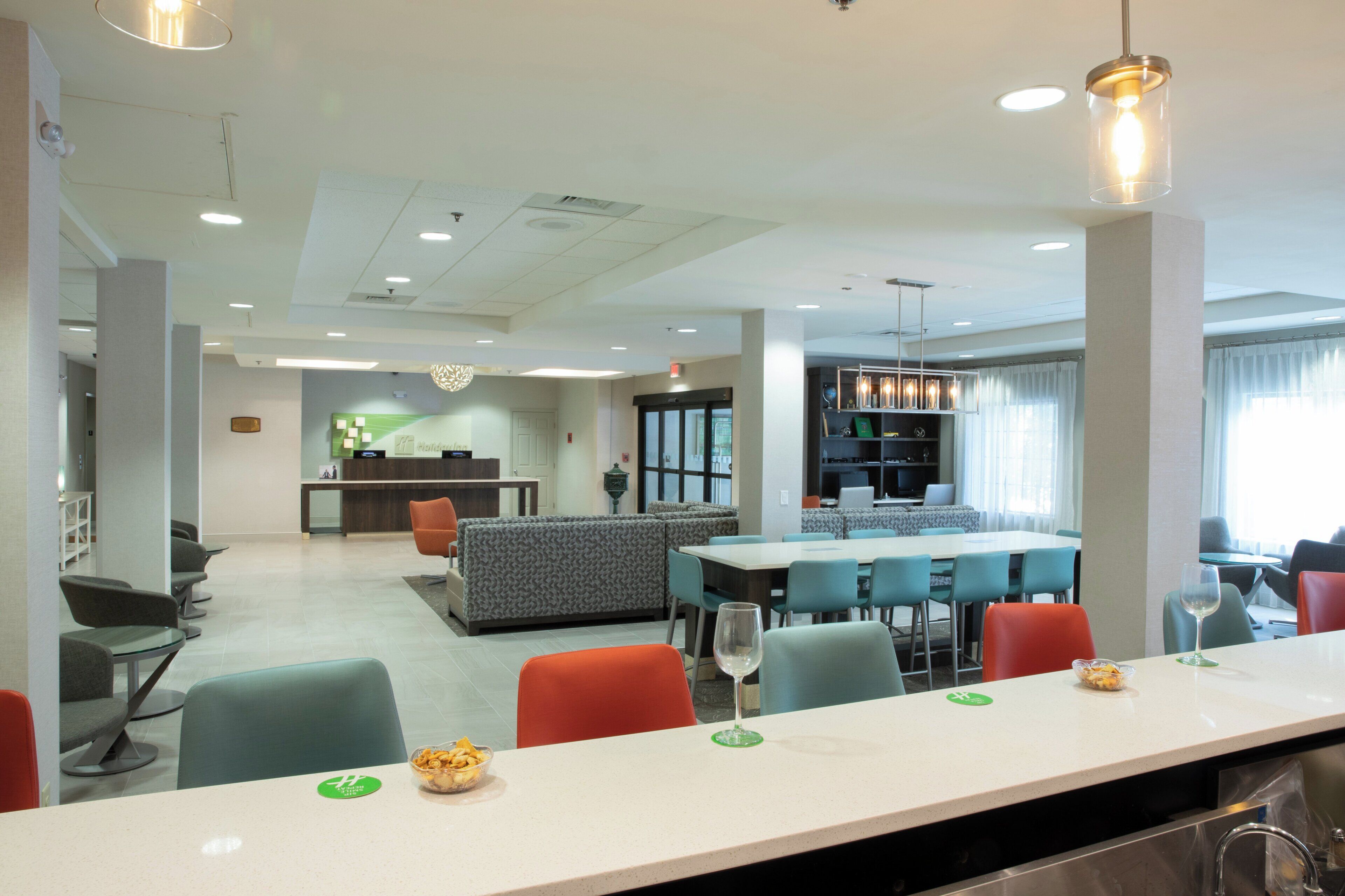A hotel lobby with a reception desk, seating area, and a dining space with tables and chairs.