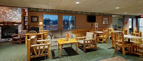A cozy lodge with a stone fireplace, wooden furniture, and large windows offering views of the outdoors.