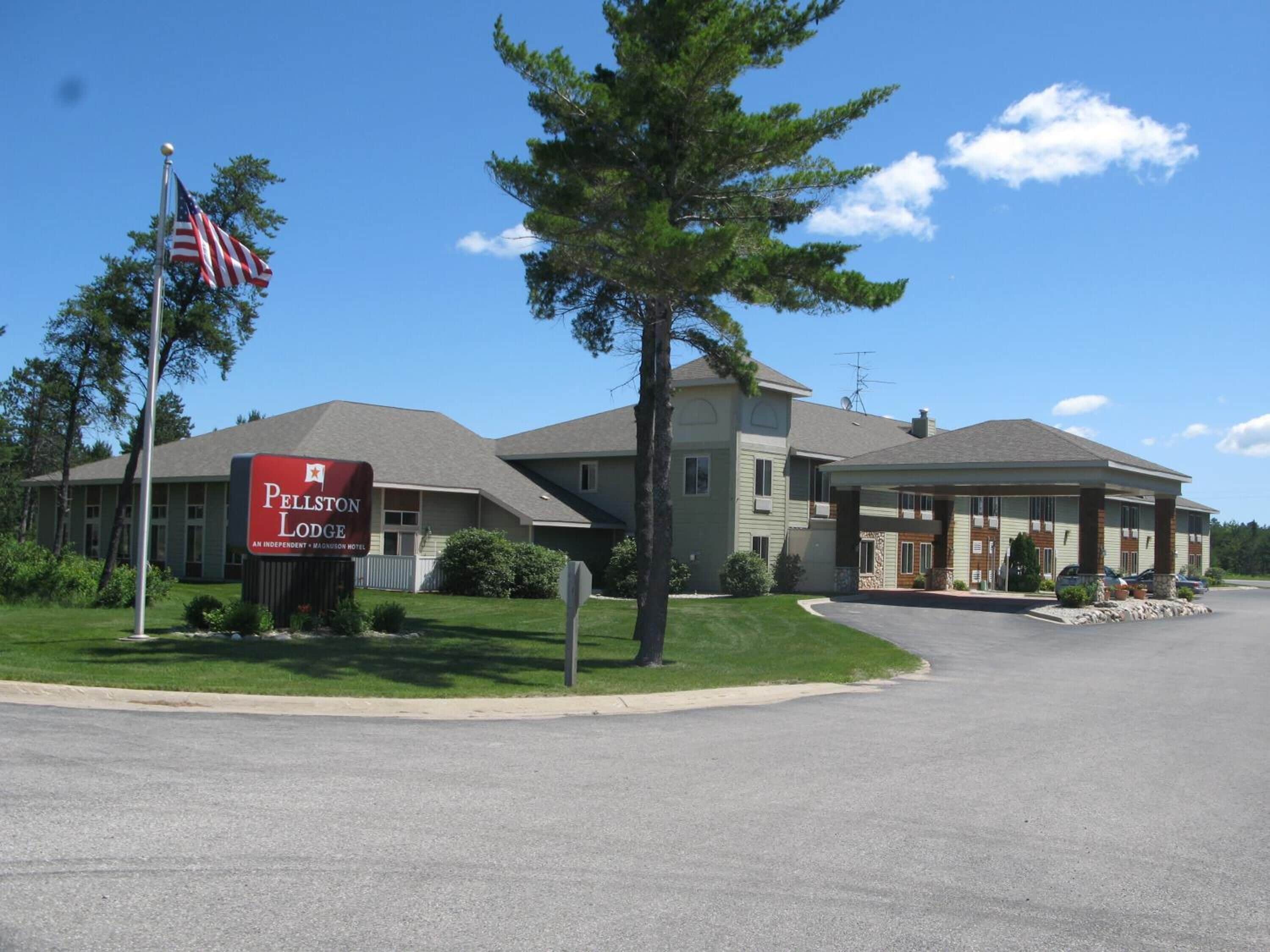 A hotel with a prominent sign, a flag, and a well-maintained lawn.