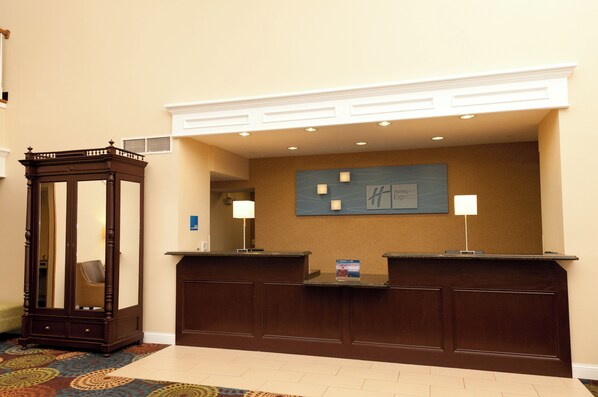 A reception desk with a wooden finish, a mirror, and a wall-mounted sign.