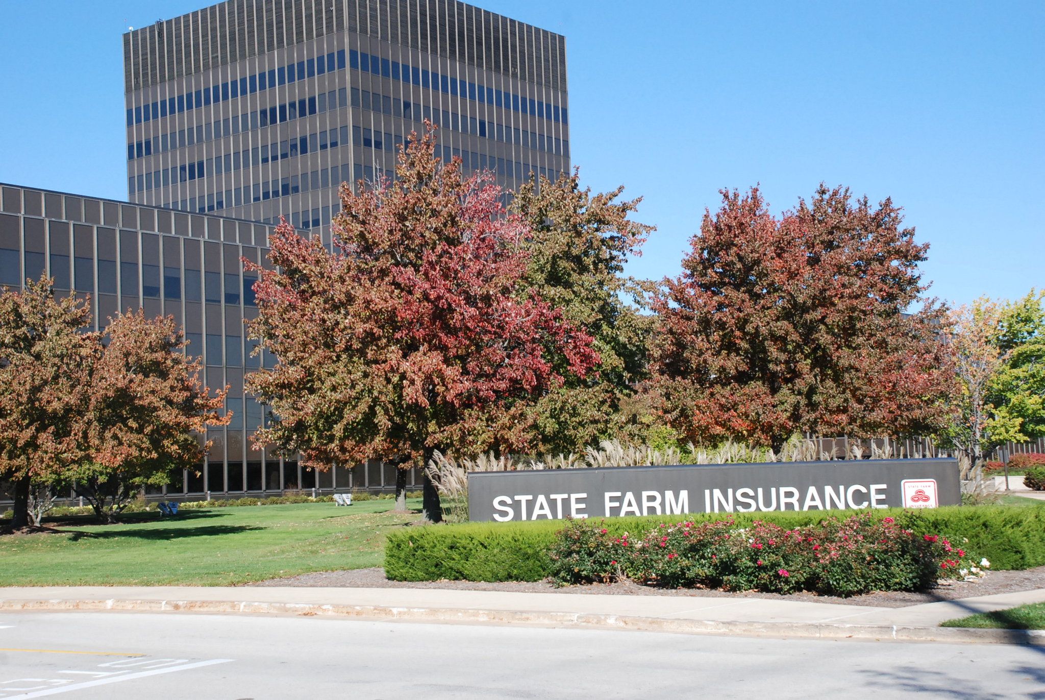 Un edificio con un letrero que dice 'State Farm Insurance' frente a una estructura moderna de vidrio.