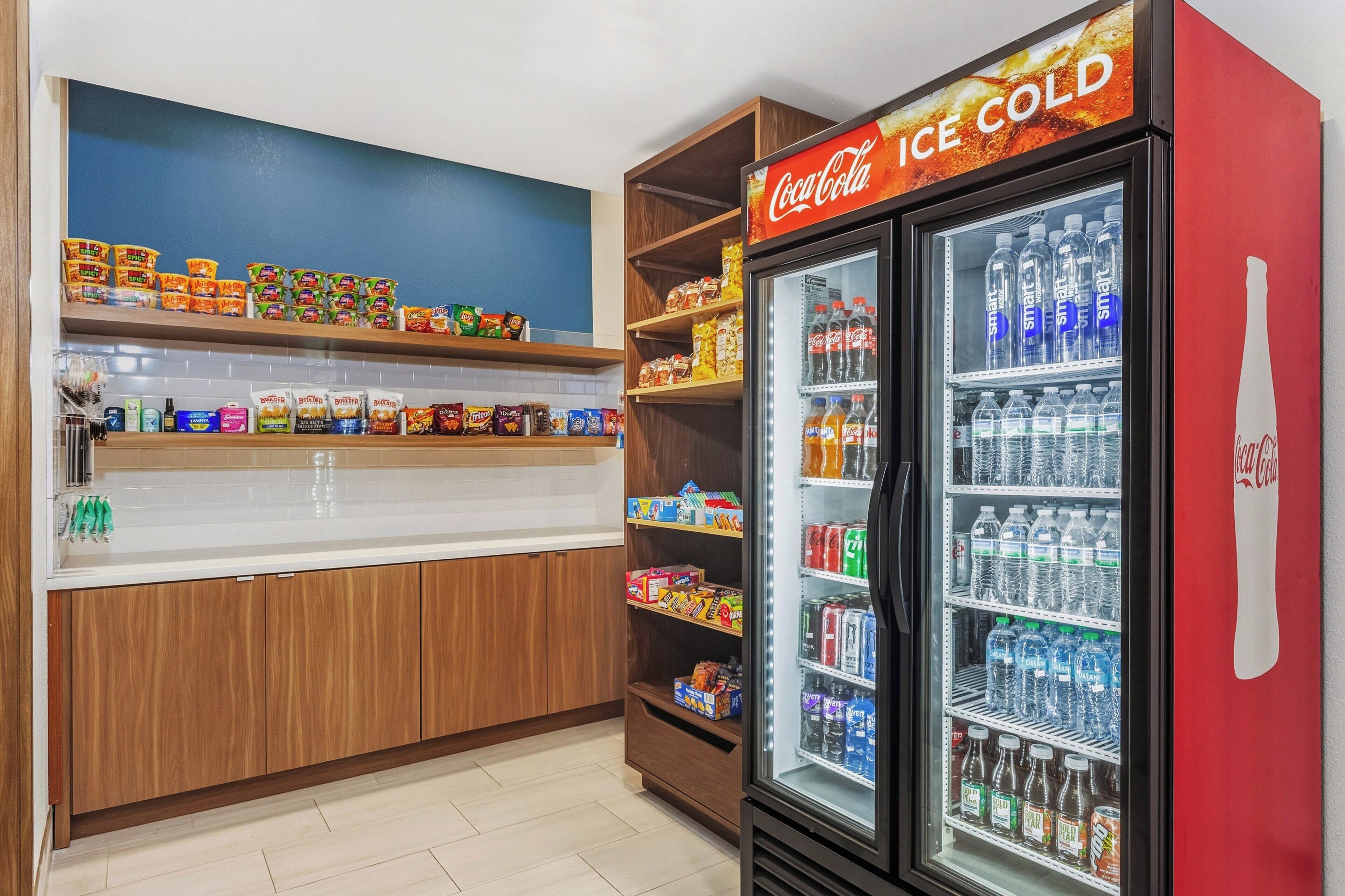 A vending machine area with snacks and beverages, including a Coca-Cola refrigerator.