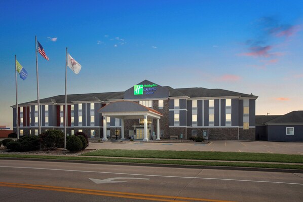 A Holiday Inn Express hotel with a covered entrance, multiple flags, and a parking lot.