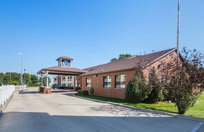 A building with a covered entrance, a clock tower, and a brick facade. - Motel 6 Waterloo, IA - Crossroads Mall - Cedar Falls (Waterloo)
