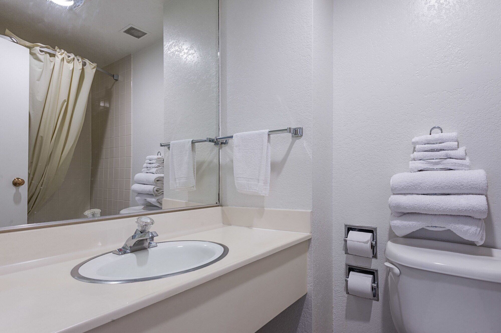 A bathroom with a sink, mirror, towel rack, and toilet.