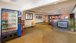 Een hotel lobby met een automaat, een open haard en een zithoek.