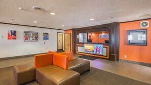 Een lobby met een receptiebalie, zithoek en een muur met ingelijste foto's.