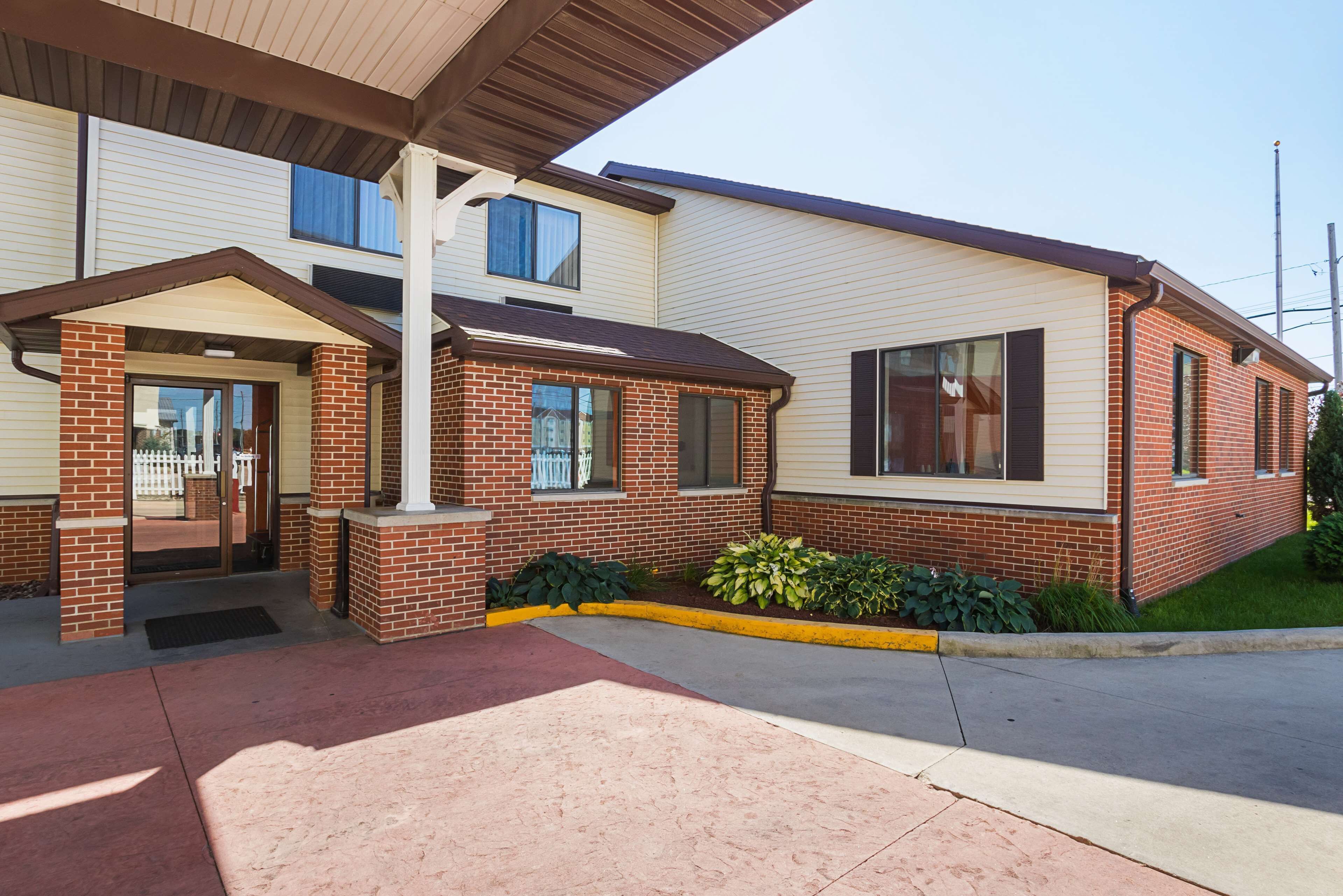 A two-story building with a brick facade, a covered entrance, and a small garden area.