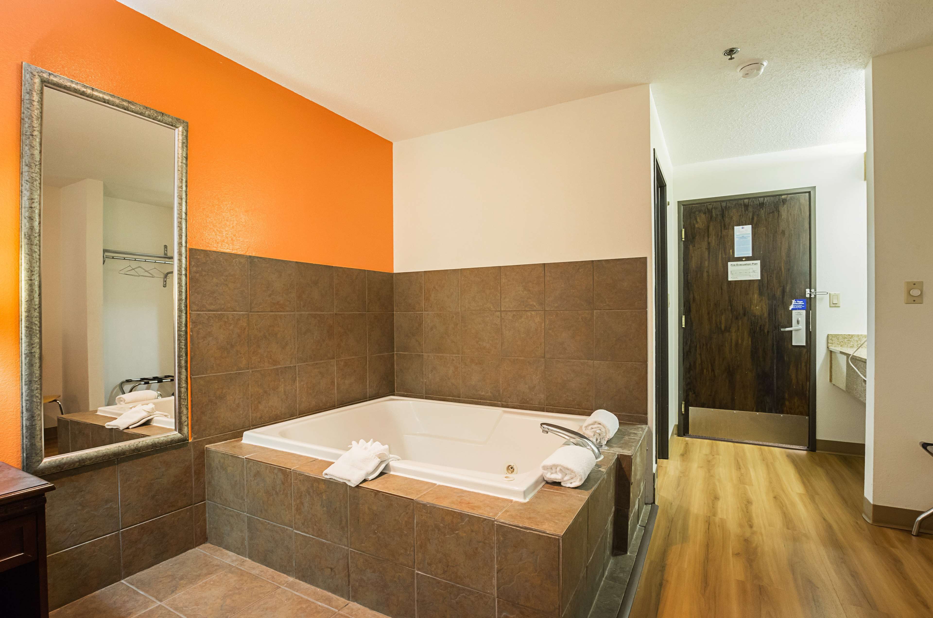 Un baño moderno con una bañera grande, un espejo y suelo de madera.