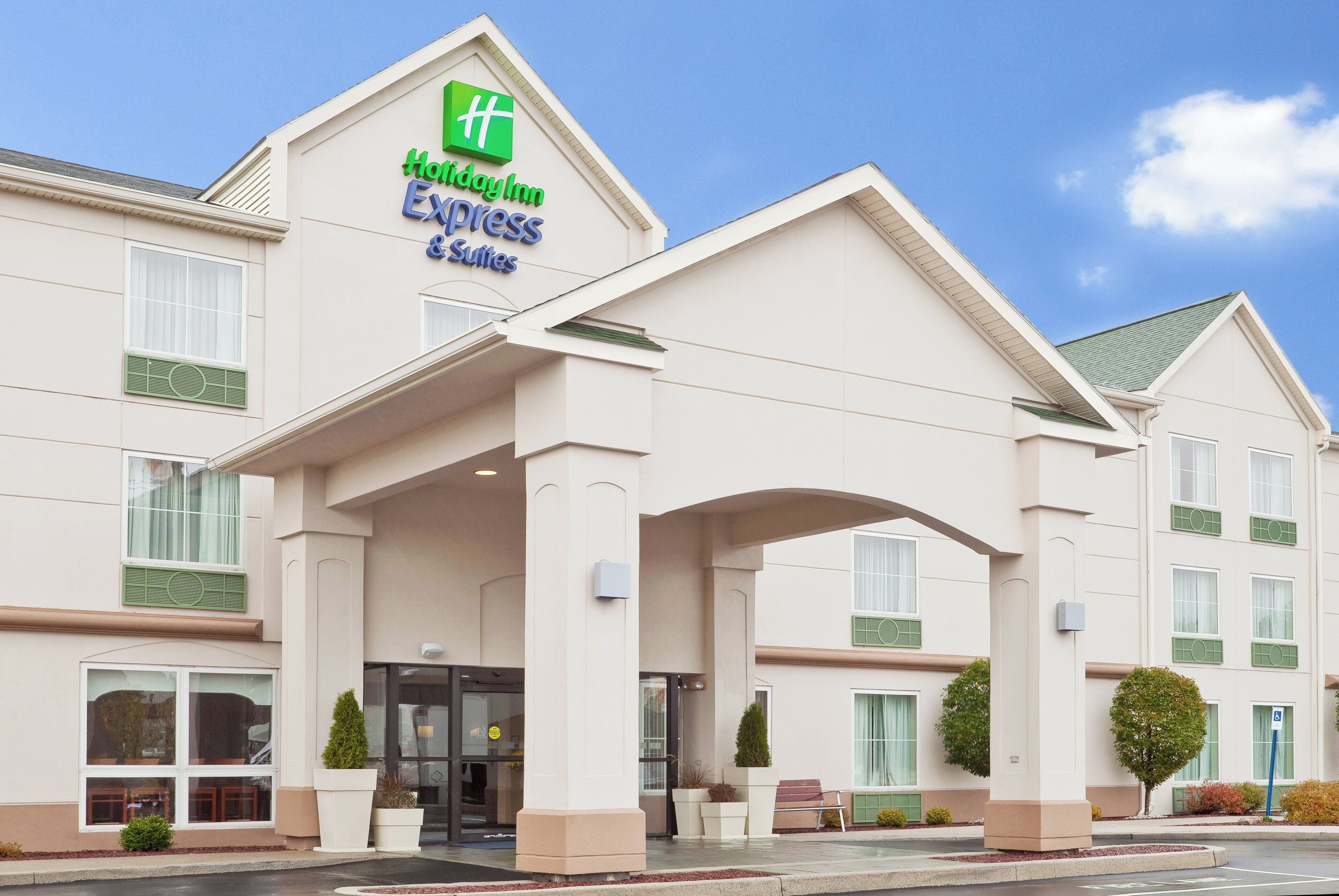 Ein Holiday Inn Express Suites Gebäude mit einem markanten Eingang, großen Fenstern und blauem Himmel.
