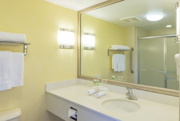 A bathroom with a sink, mirror, towel rack, and shower.
