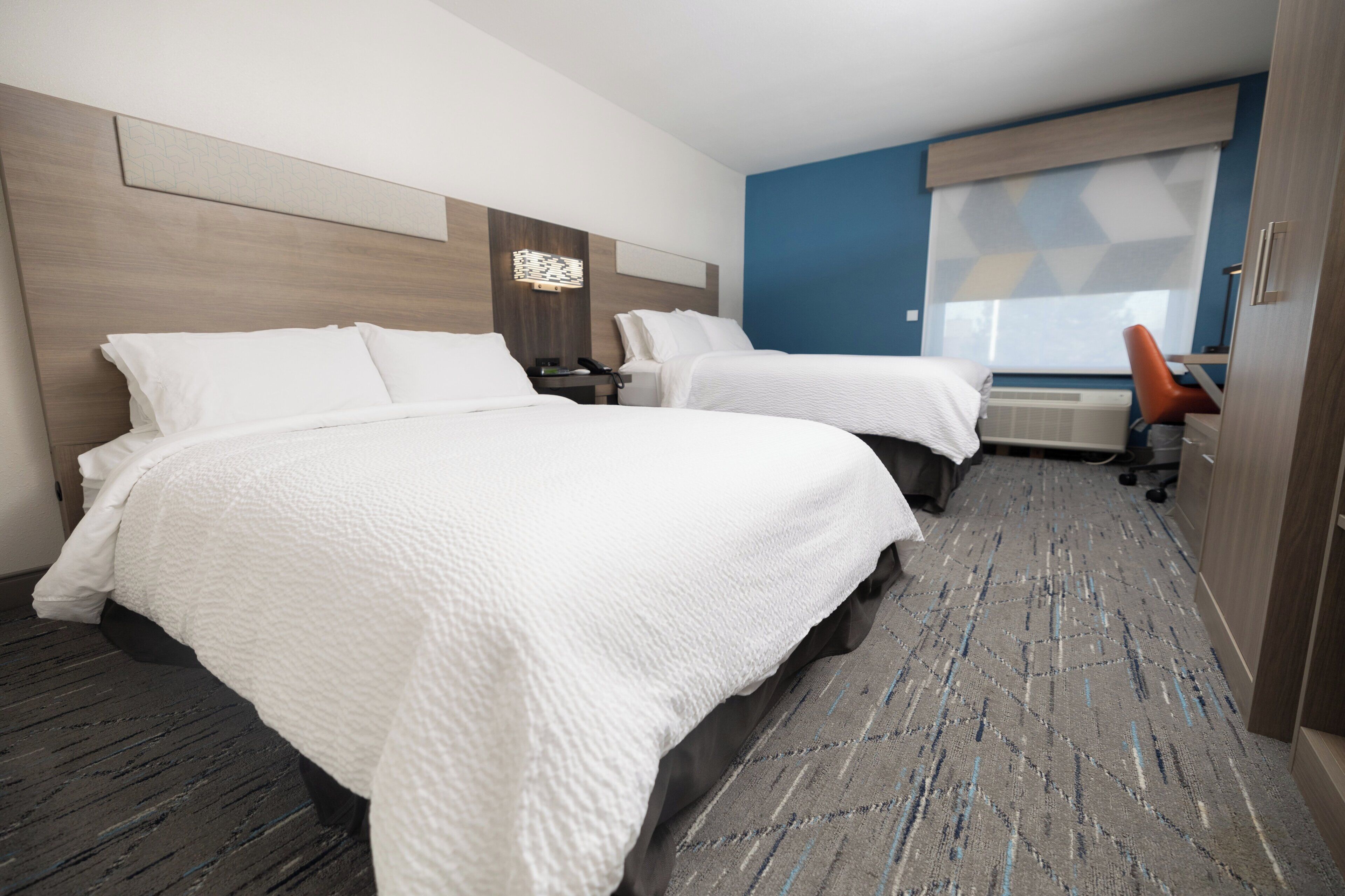 Ett hotellrum med två sängar, ett skrivbord och en stol.