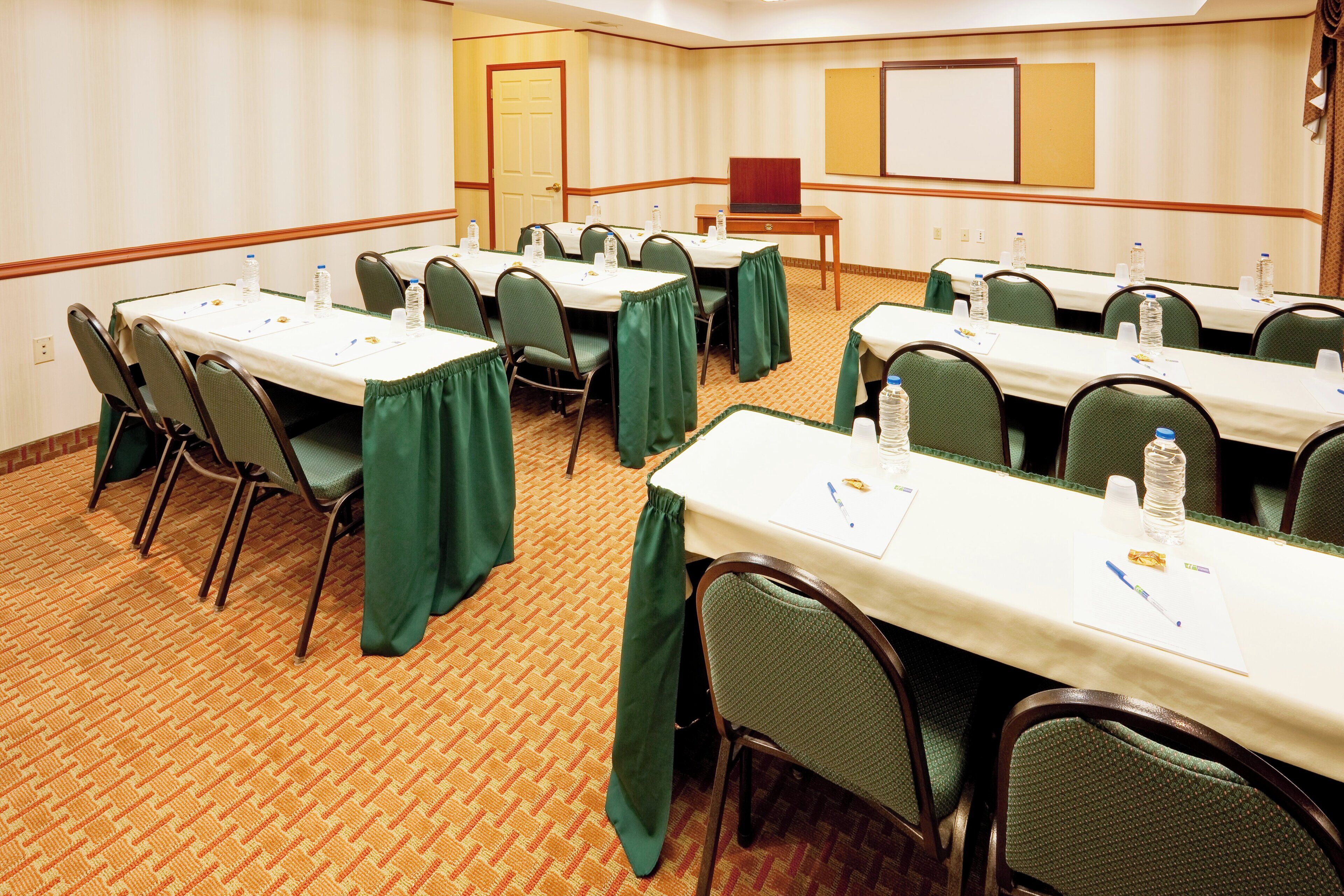 A conference room with multiple tables, chairs, and a whiteboard.