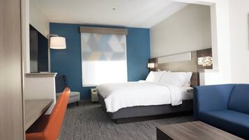 Una habitación de hotel con cama, escritorio, silla, sofá y ventana.