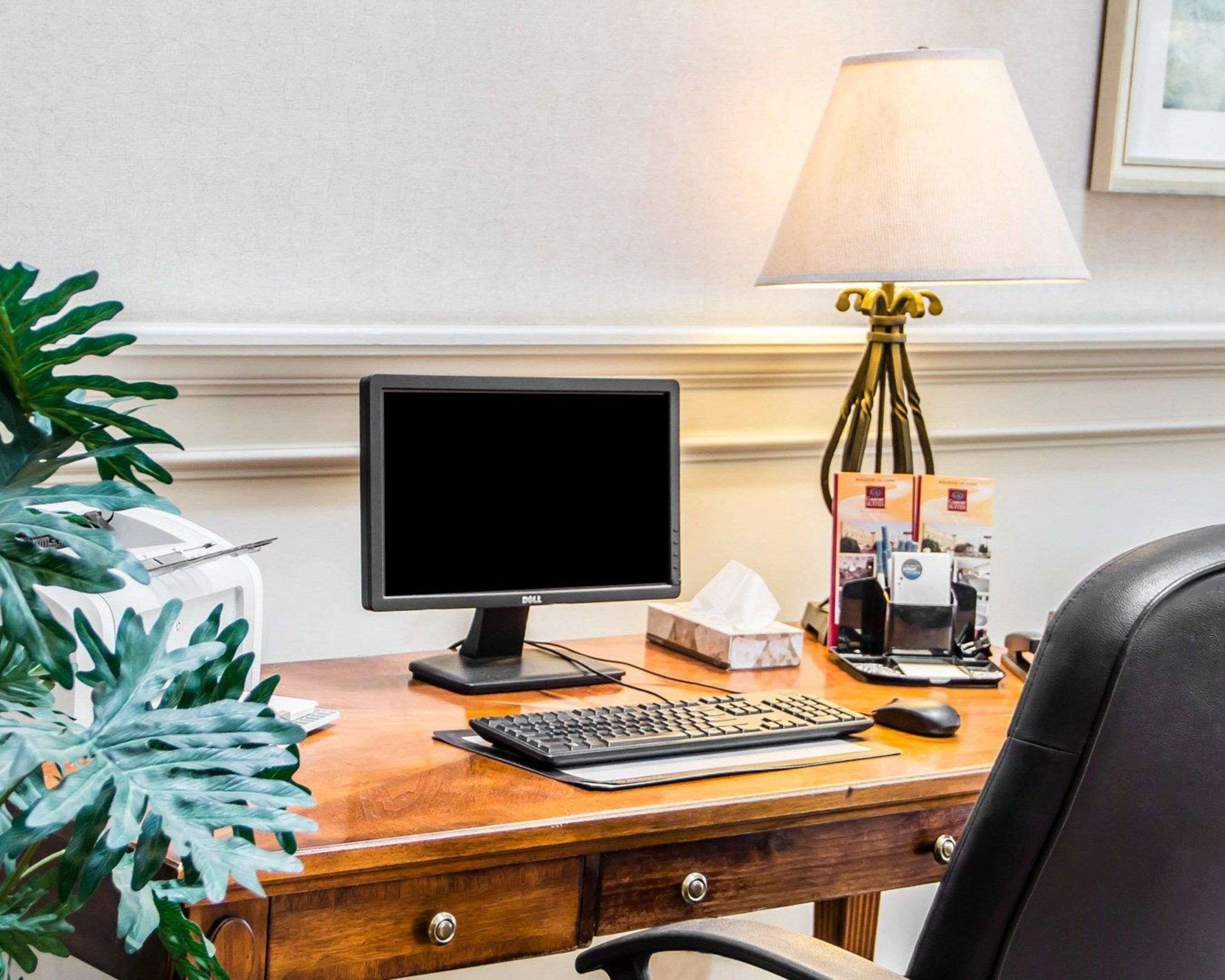 A wooden desk with a computer, keyboard, mouse, and a lamp.