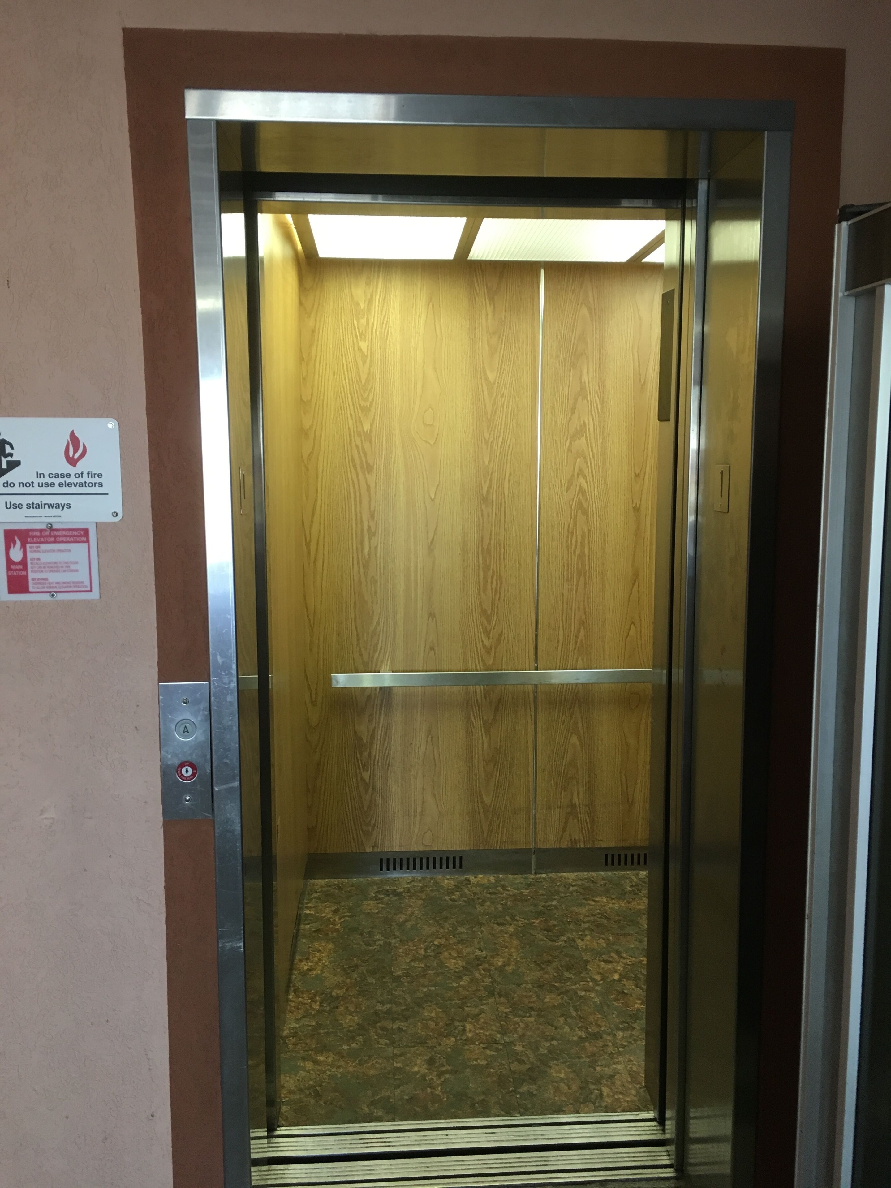 An elevator with a wooden interior, emergency operation instructions, and a control panel with buttons.