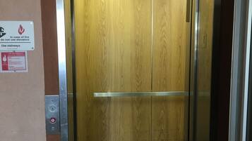 An elevator with a wooden interior, emergency operation instructions, and a control panel with buttons.