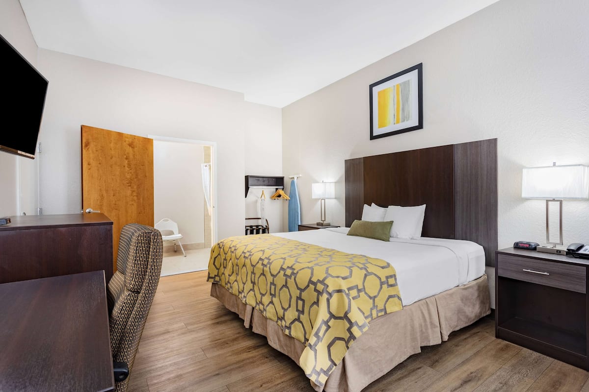 Une chambre d’hôtel comprenant un lit, une table de chevet, une lampe et un bureau avec une chaise.