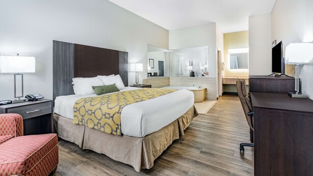 A hotel room with a bed, bedside table, chair, desk, and a large mirror.