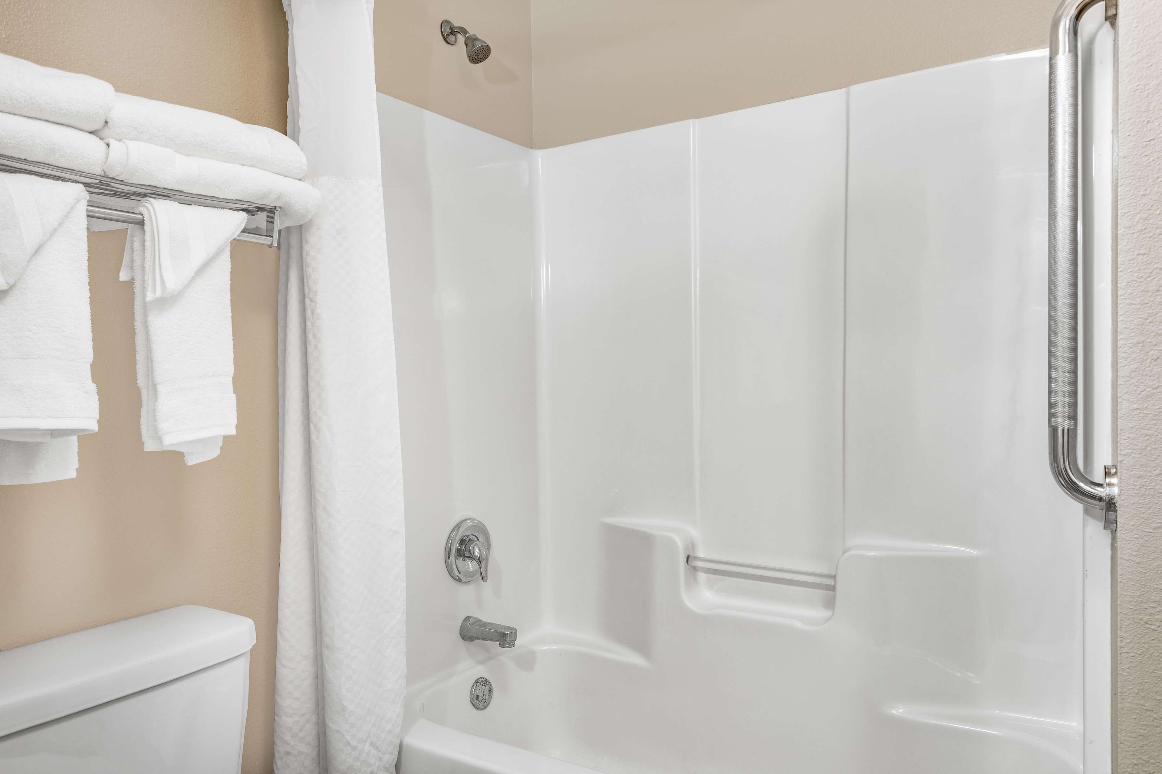 A bathroom with a bathtub, a toilet, and a towel rack with folded towels.
