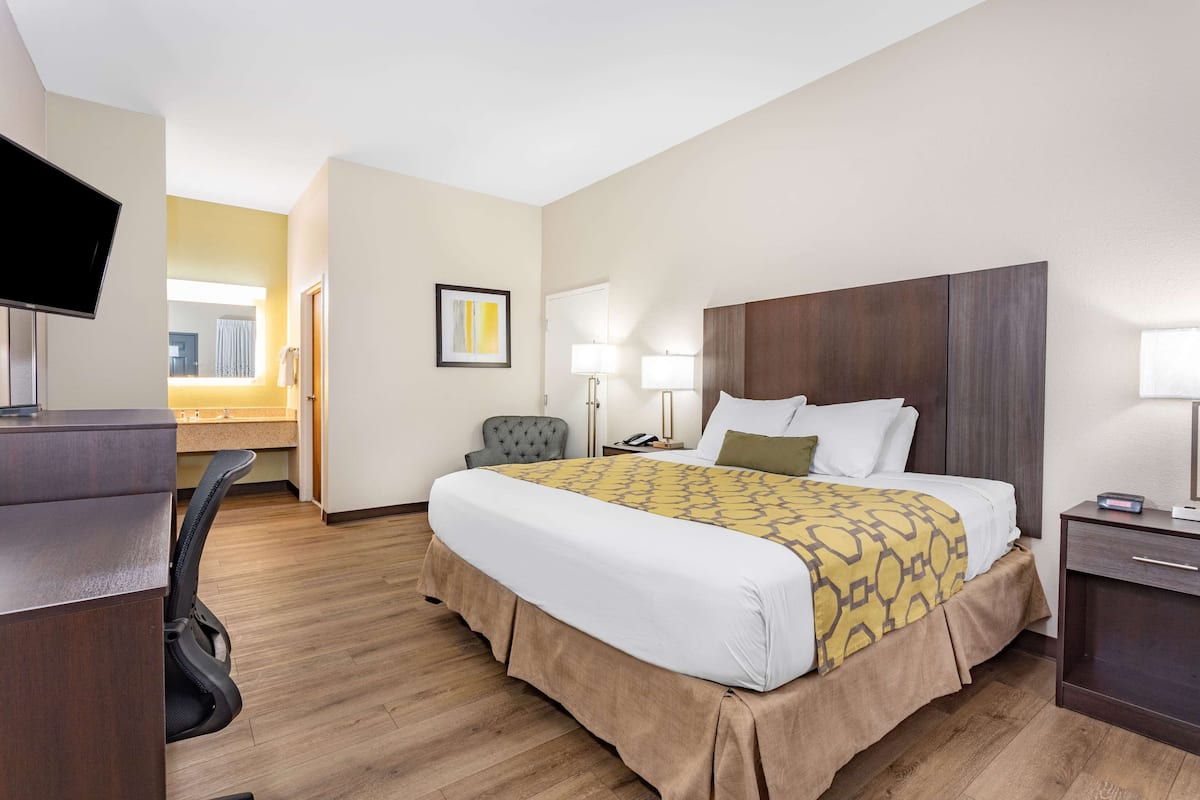 Une chambre d’hôtel comprenant un lit, une table de chevet, une lampe et un bureau avec une chaise.