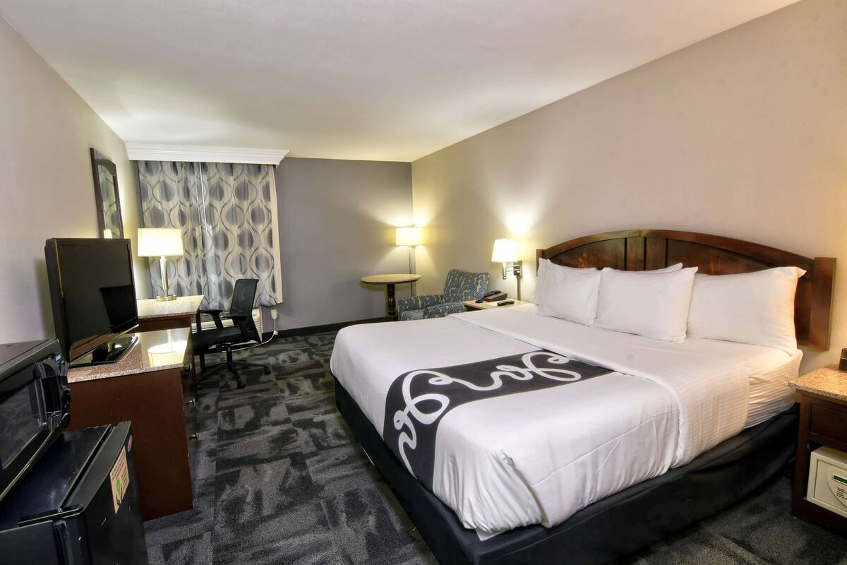 A hotel room with a large bed, a desk with a computer, and a TV.