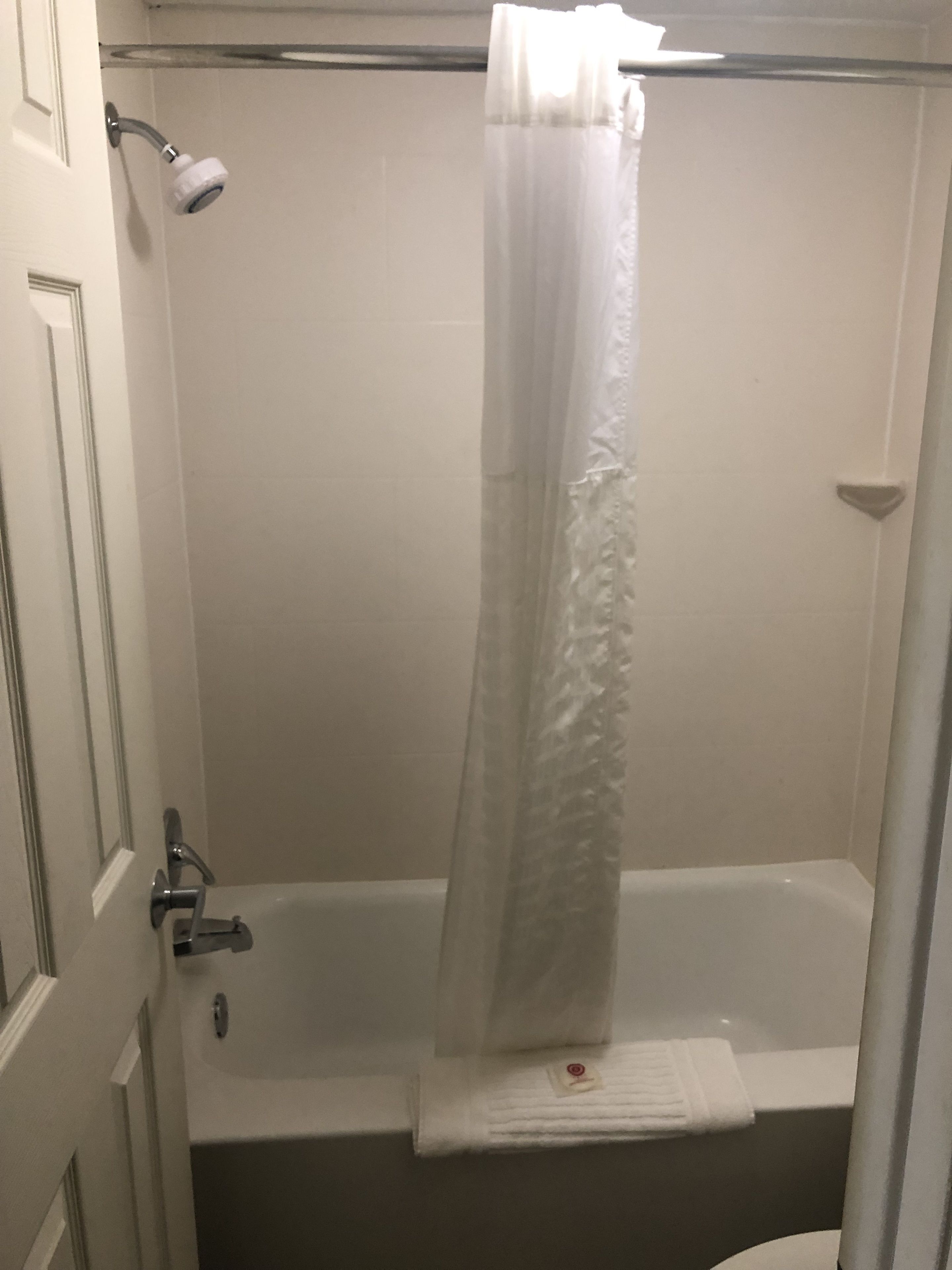 A bathroom with a bathtub, a shower curtain, and a towel rack.