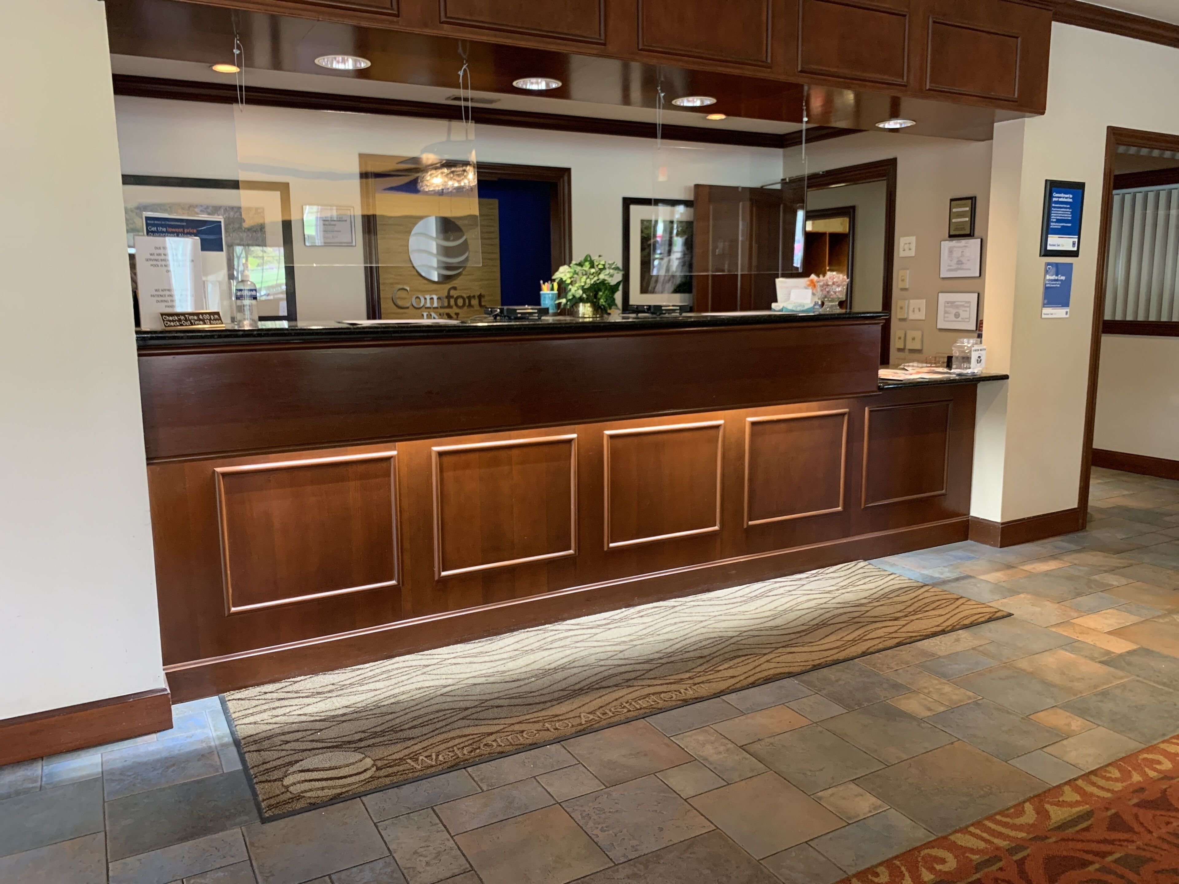 A reception area with a wooden counter, a reception desk, and a patterned rug on the floor.