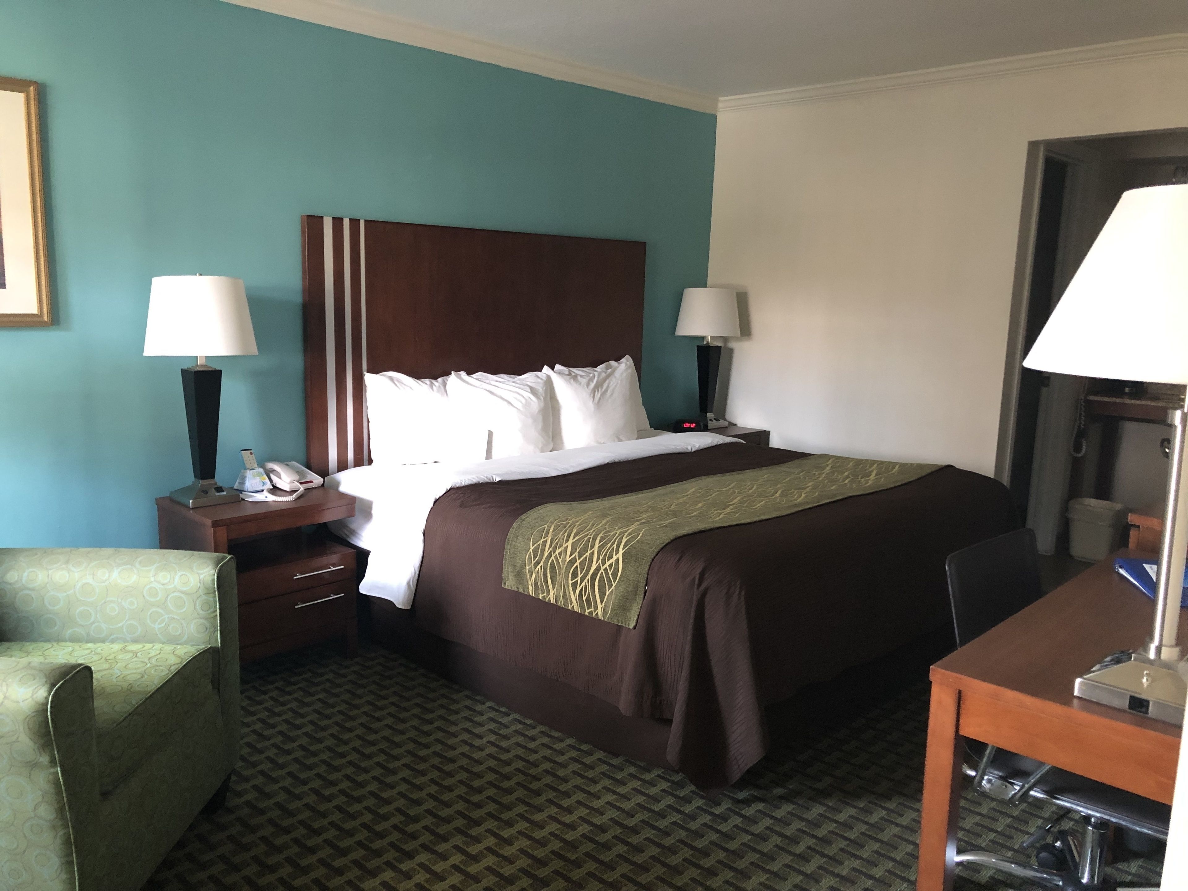 A hotel room with a large bed, two bedside tables with lamps, a desk, and a chair.