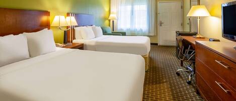 A hotel room with two beds, a desk, a chair, a TV, and a wardrobe.