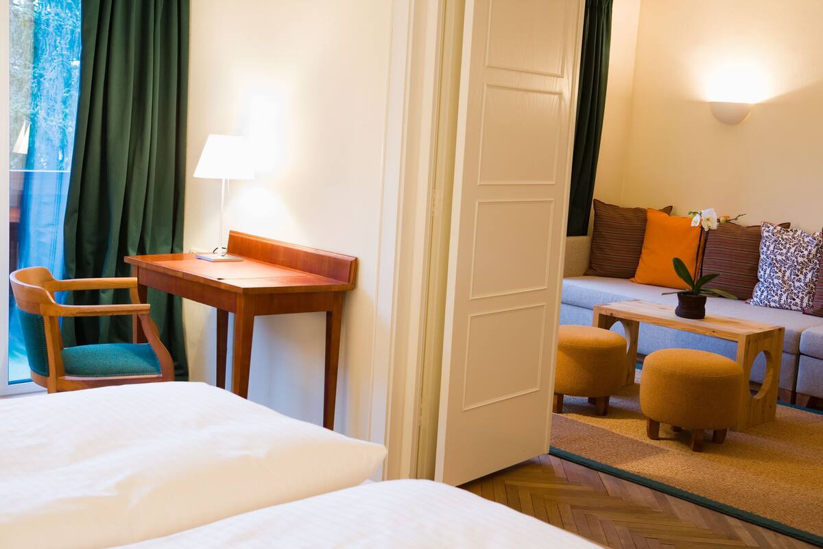 Una habitación de hotel con una cama, un escritorio, una silla, un sofá y una mesita con una planta.