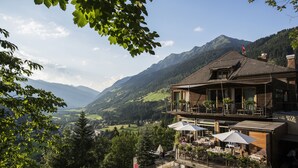 Un edificio de dos pisos con terraza al aire libre y vistas a la montaña.