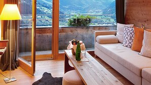 Una habitación acogedora con un banco de madera, un sofá y un ventanal con vistas a la montaña.
